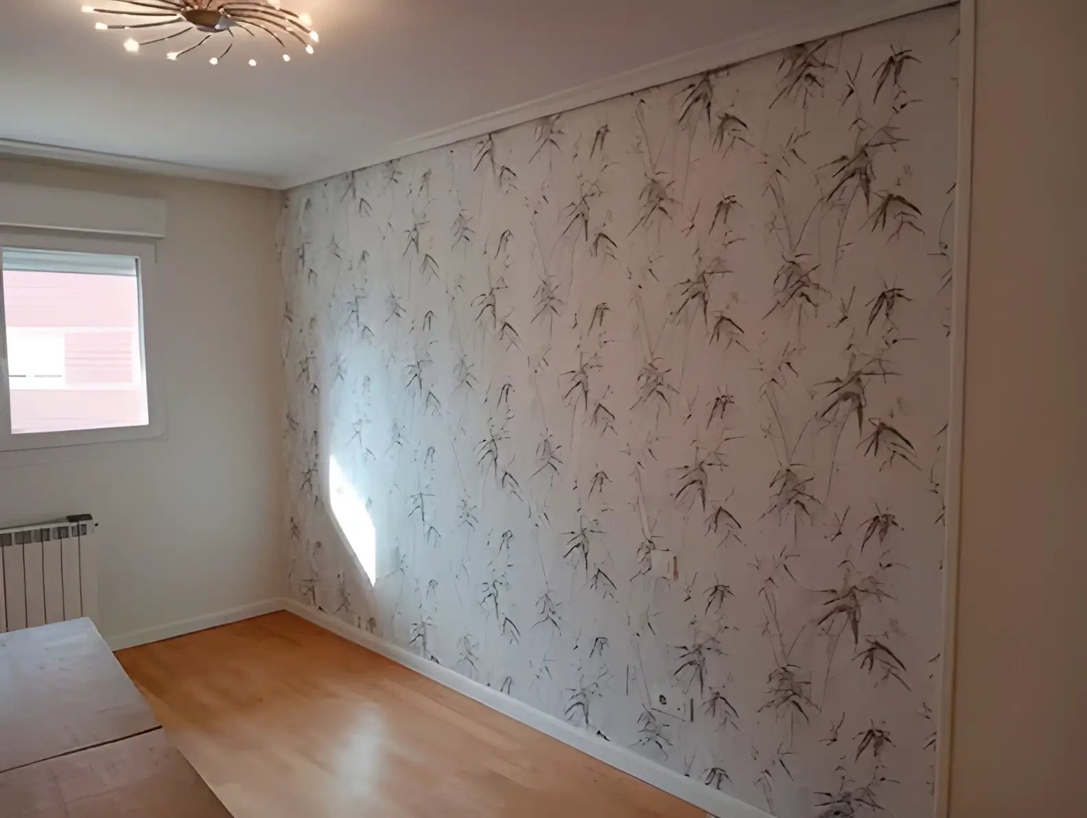 Los Pintores Marbella colocando papel pintado en pared de acento de habitación luminosa